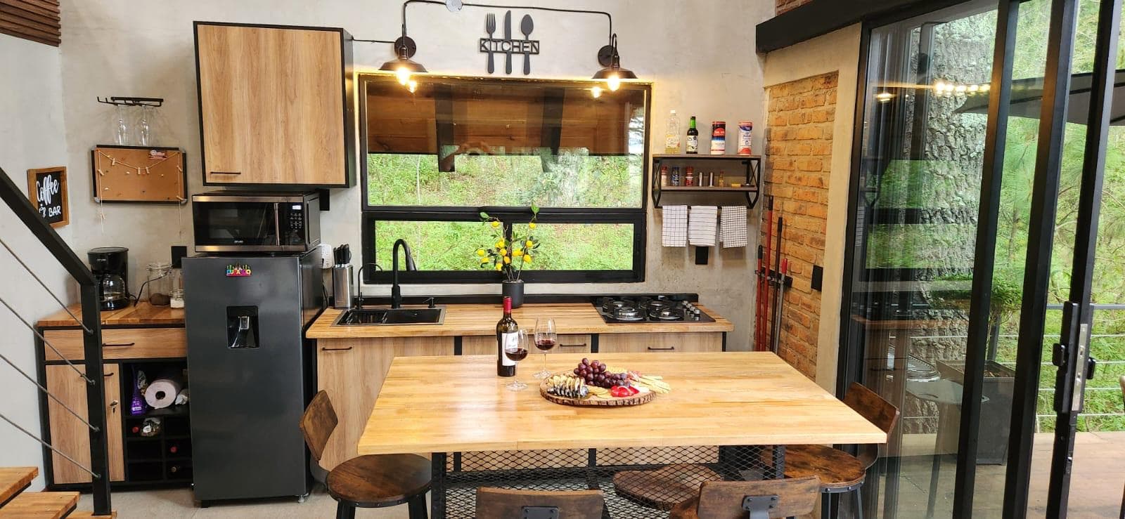 Cocina de madera con isla central y ventanales al bosque